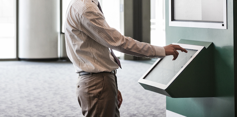 Businessman at an information kiosk in a large lobby area.