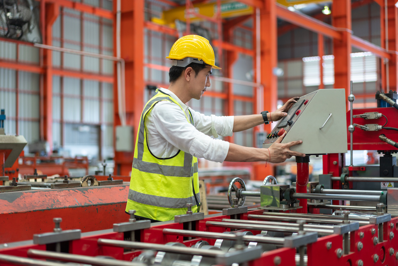 Asian male engineer wearing safety vest with helmet checking and control machine at factory manufacturing industrial.Preventive Maintenance concept