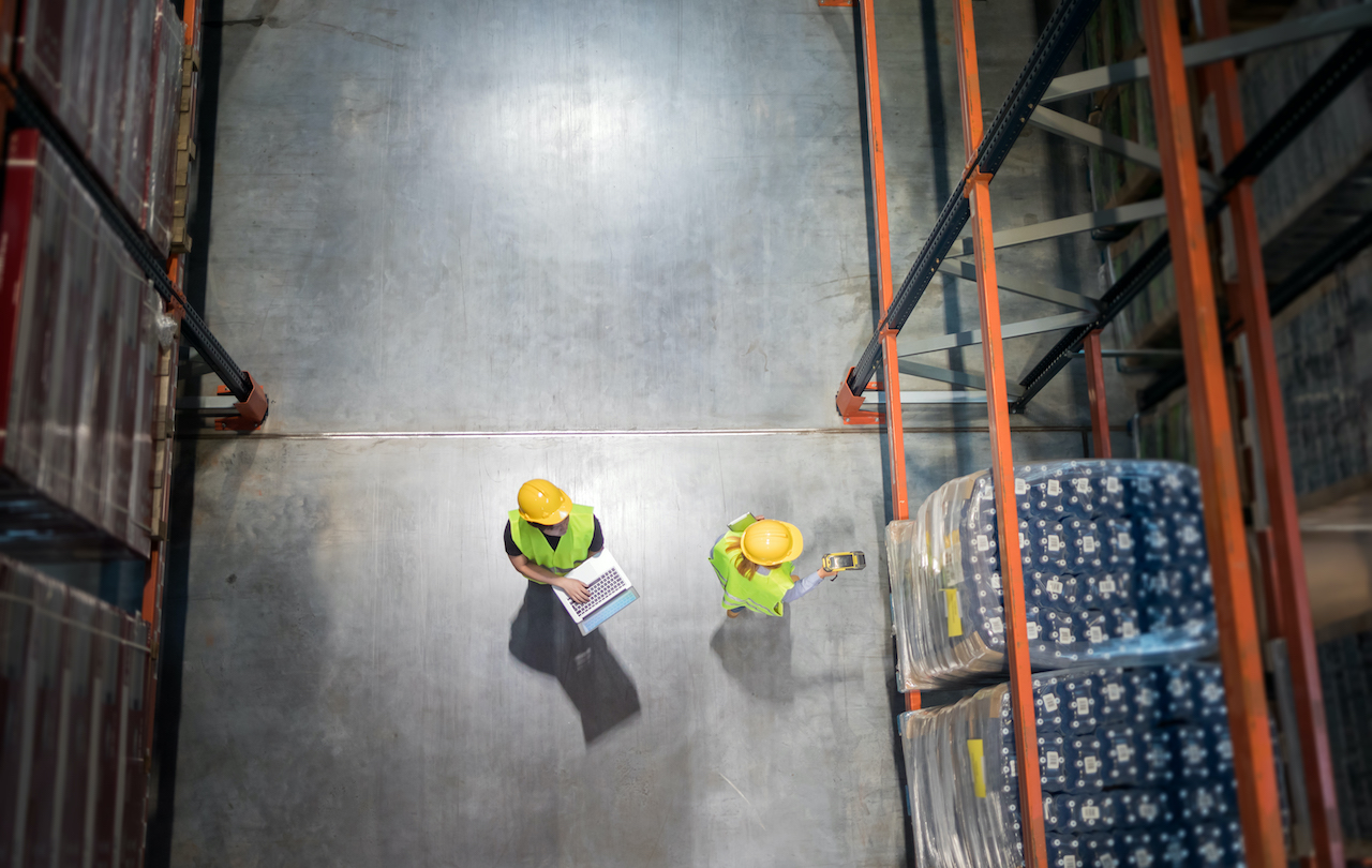 Checking warehouse database of inventory with laptop, view from above. Warehouse efficiency