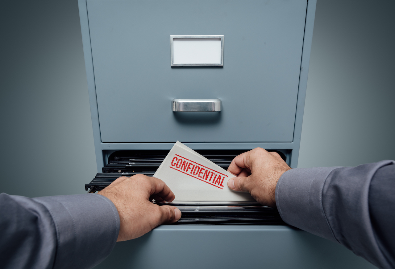 A man's hand holding a confidential file being PDPA compliant