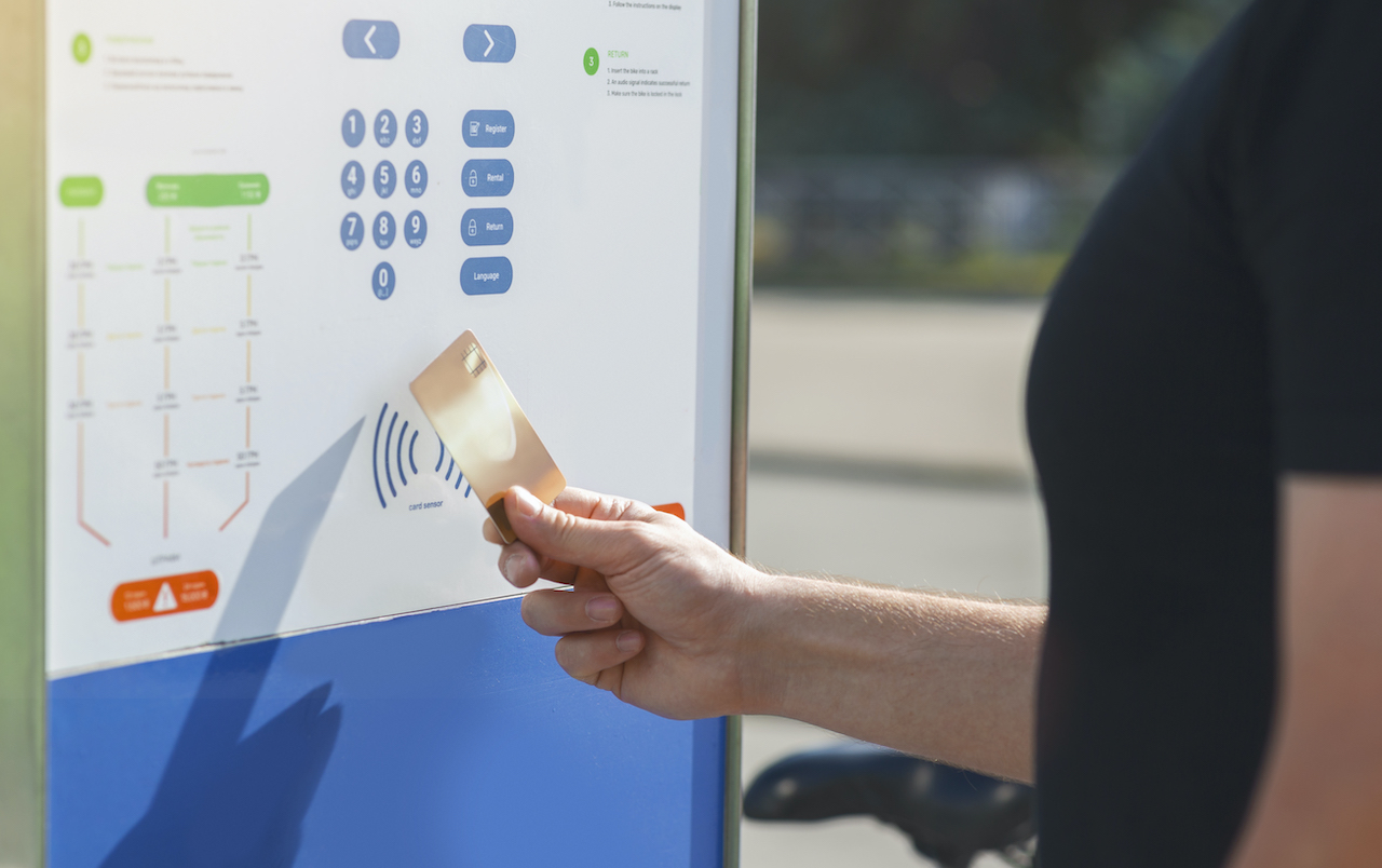 A man scanning an RFID card to a kiosk for touchless access control in contactless visitor management.