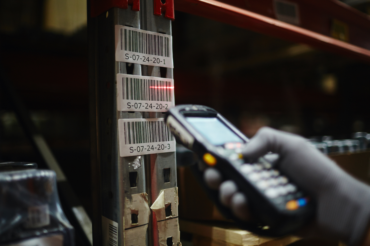 A person using a business-grade barcode scanner scanning a barcode in a warehouse facility.