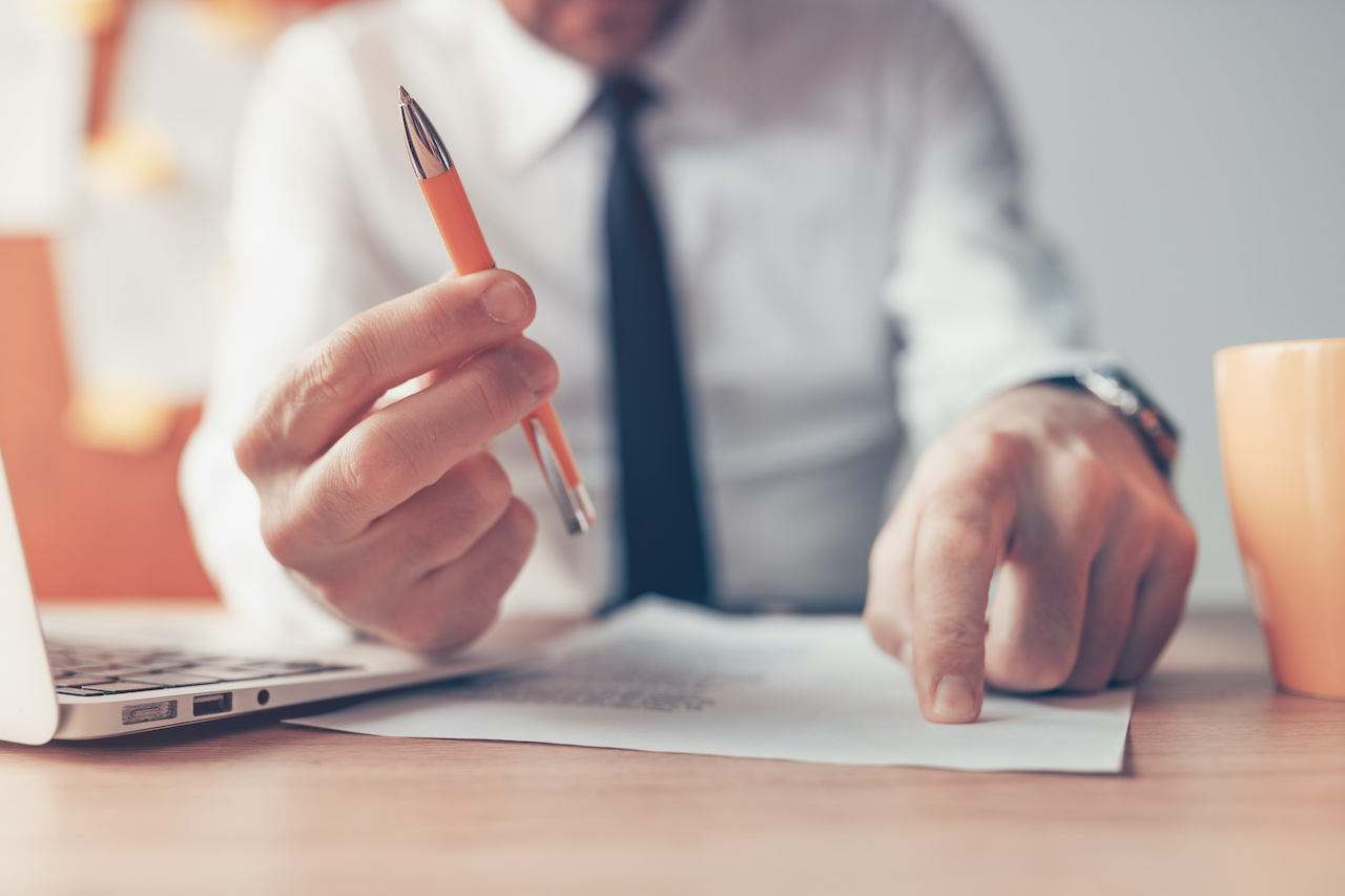 Business owner pointing on a contract and holding a pen showing a business obligation to be PDPA compliant.