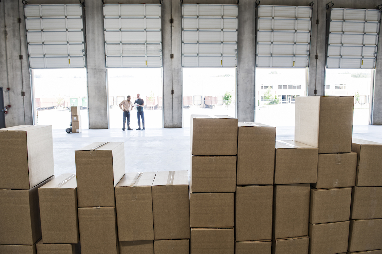 Team workers checking on pile of boxes for inventory management.