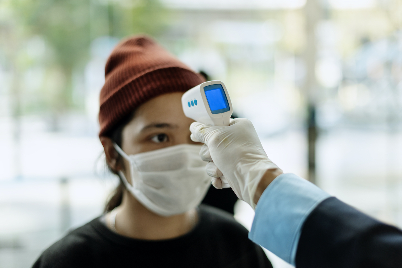 A man scanning a temperature scanner to a visitor for a contactless visitor management process