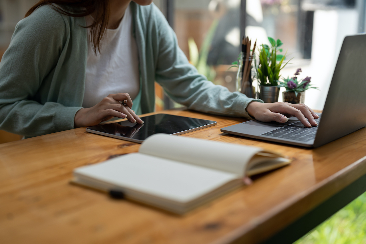 Asian woman writing making list taking notes in notepad and digital tablet working or learning on laptop indoors- educational course or training, seminar, education online concept.