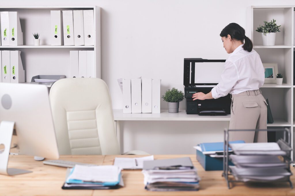 Rear view of office manager in blouse choosing amount of copies while making scan of documents on printer