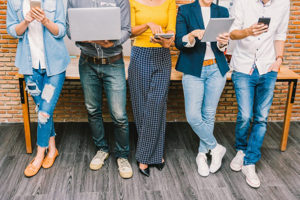 Group Of Asian and Multiethnic Business people with casual suit using the technology mobile, tablet, laptop and computer for working or social network in modern Office,people business group concept