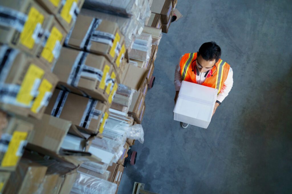 Logistics warehouse worker with a box in his hands