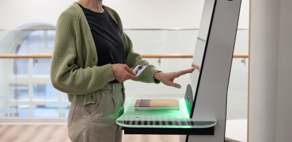 Middle-aged woman using self-service terminal in digital Visitor management kiosk, registering. Innovative technologies in visitor management.
