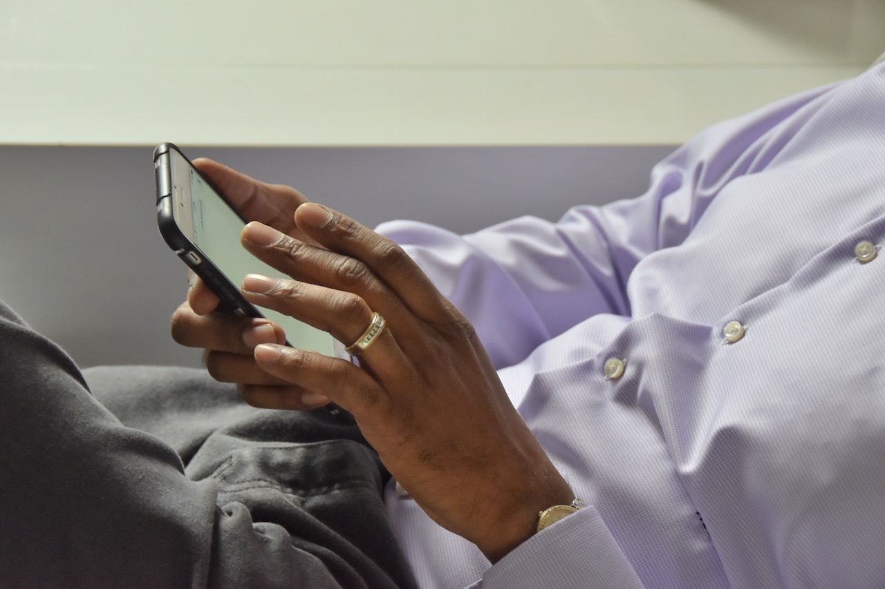 A holding a mobile phone checking on a website.