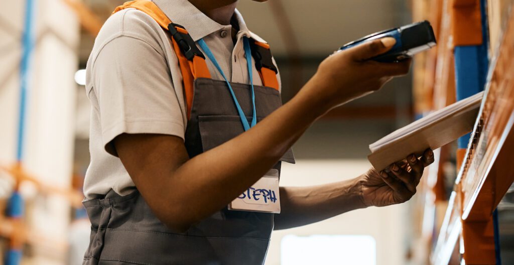 warehouse worker scanning labels on packages while working at storage compartment.