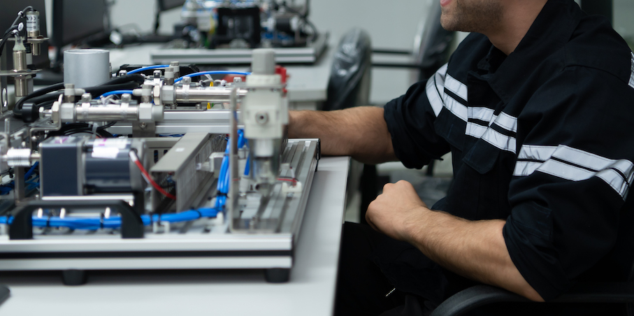 The robotic hand technology teacher is instructing new students on how to use electronic circuit boards and robotic hand commands for a variety of industrial applications.