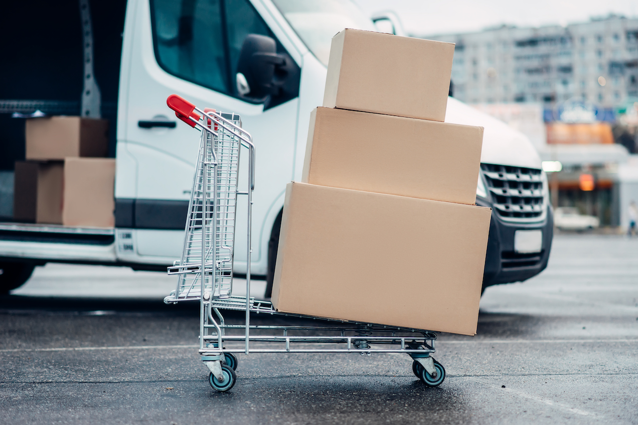 Trolley with carton boxes against truck . Distribution business. Cargo delivery. Empty, clear containers. Mail logistic and post service