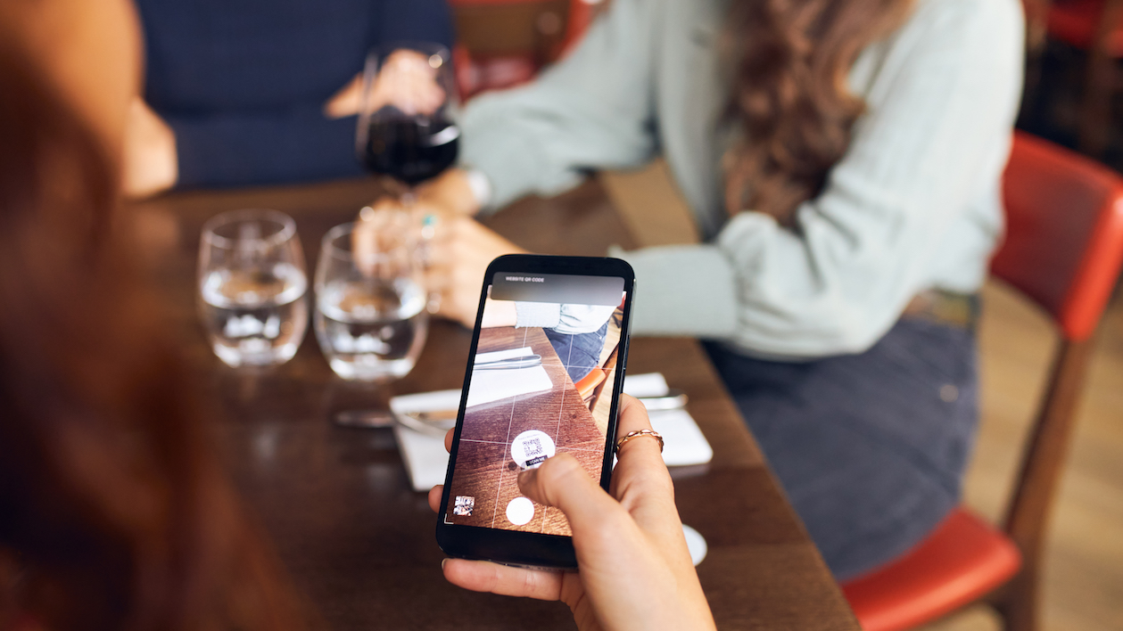 Woman scanning qr code in wine bar for ordering.