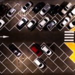 Parking Management System - Drone aerial view of parking lots with cars at night. Crowded shopping mall outdoor car park.