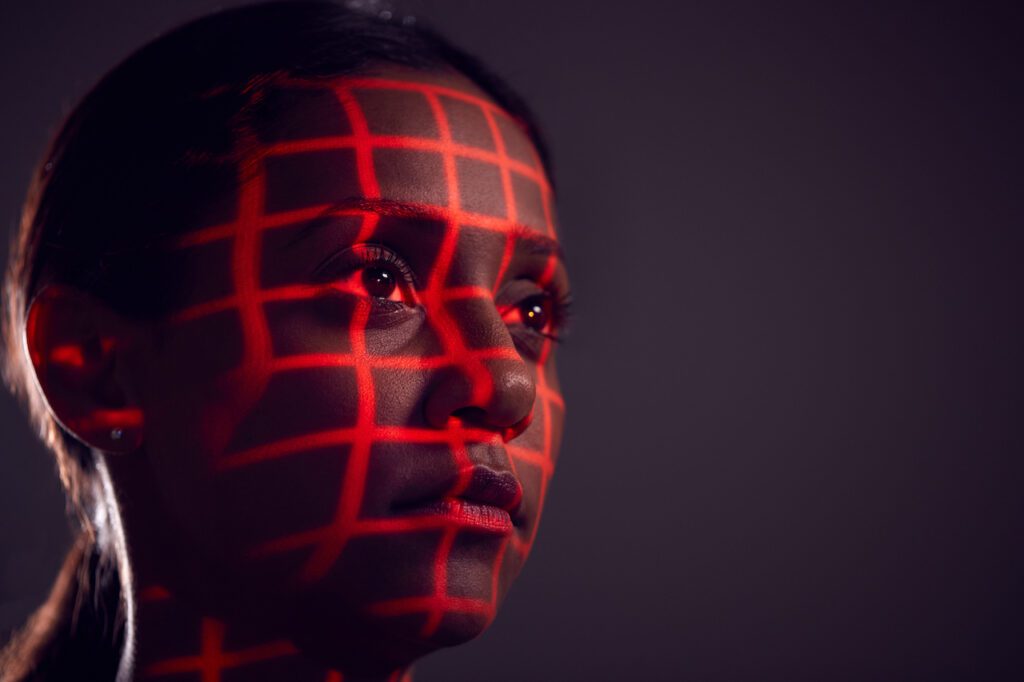 Facial Recognition Technology Concept As Woman Has Red Grid Projected Onto Face In Studio