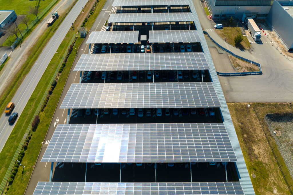 Aerial view of solar panels installed as shade roof over parking lot with parked cars for effective generation of clean electricity. Photovoltaic technology integrated in urban infrastructure for Sustainable Parking