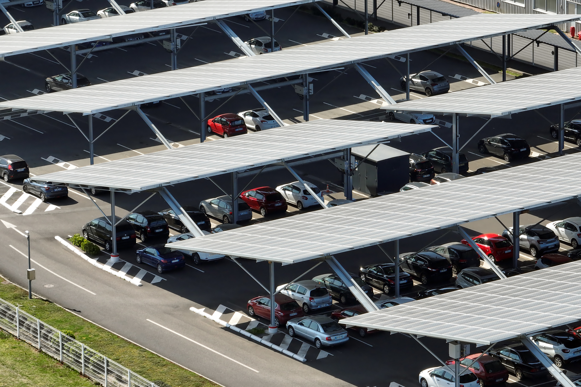 Aerial view of solar panels installed over parking lot with parked cars for effective generation of clean energy